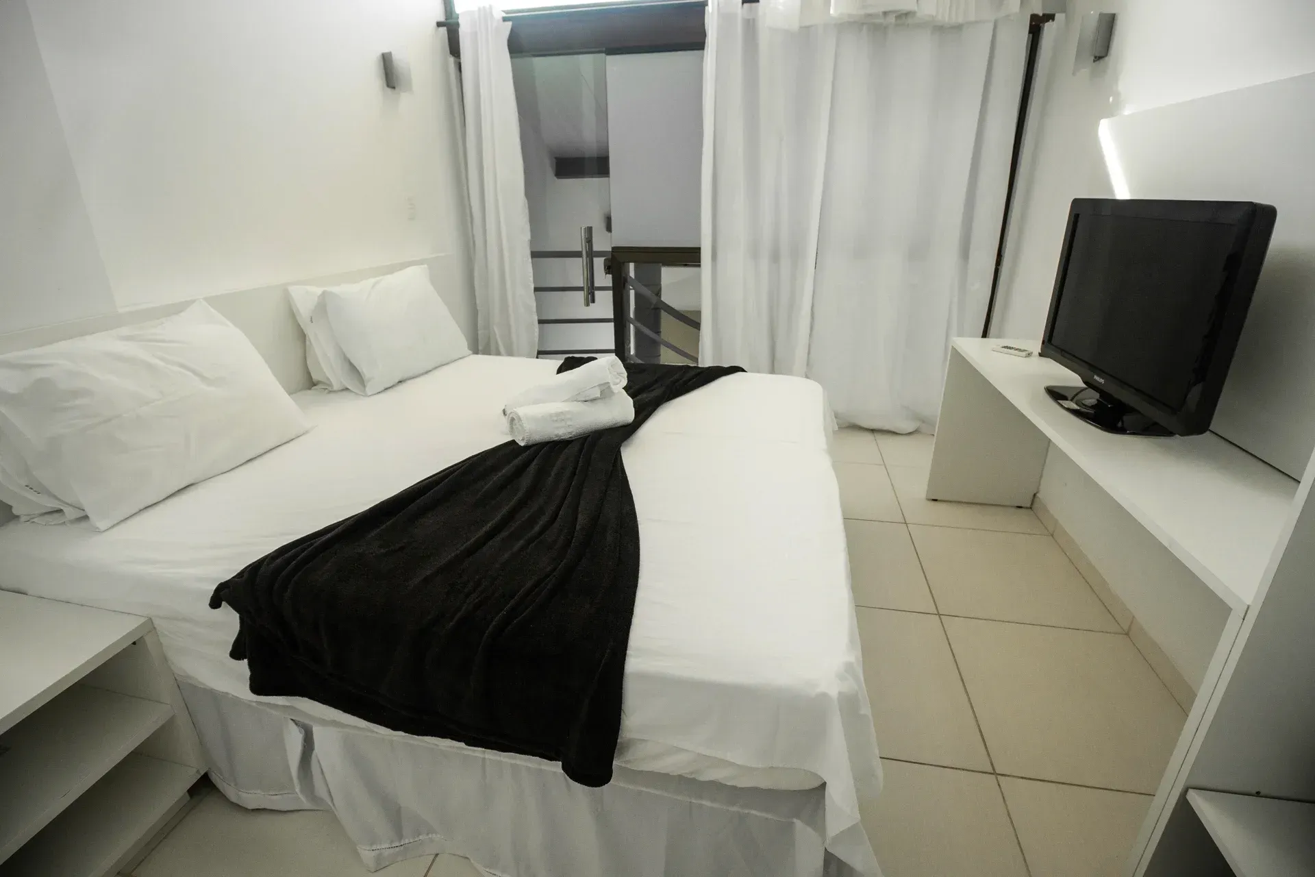 Um quarto com uma cama grande e uma TV de tela plana