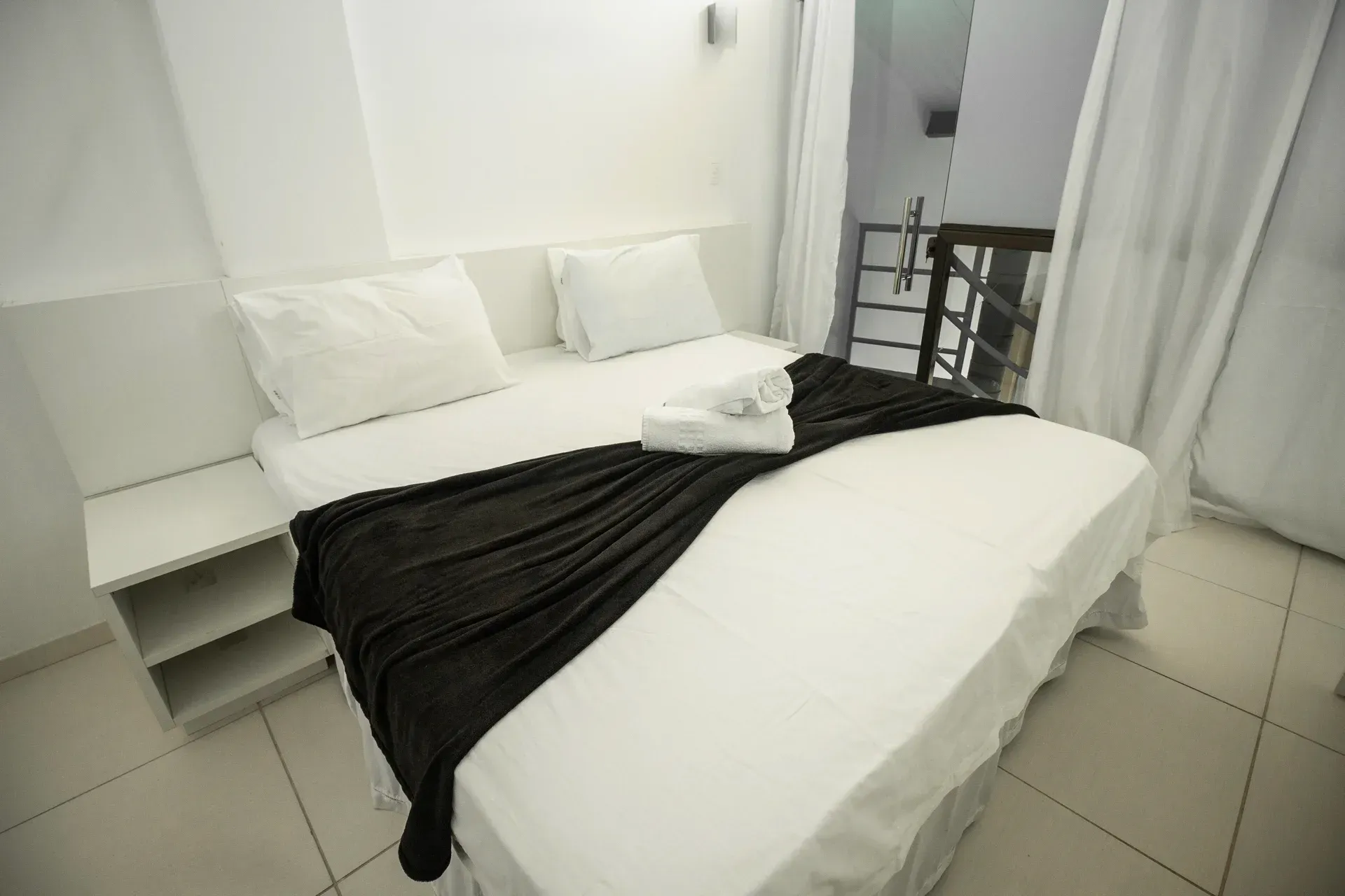 Uma cama com lençóis brancos e um cobertor preto em um quarto de hotel.