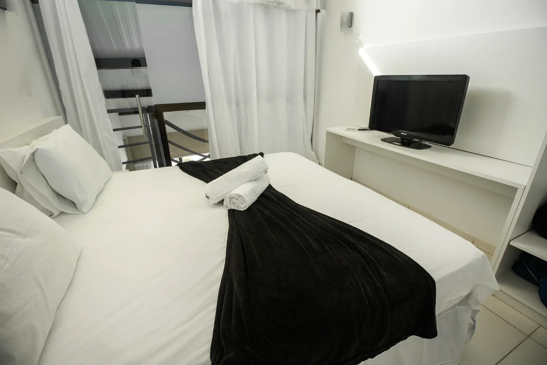 Um quarto de hotel com cama, televisão e escadas.