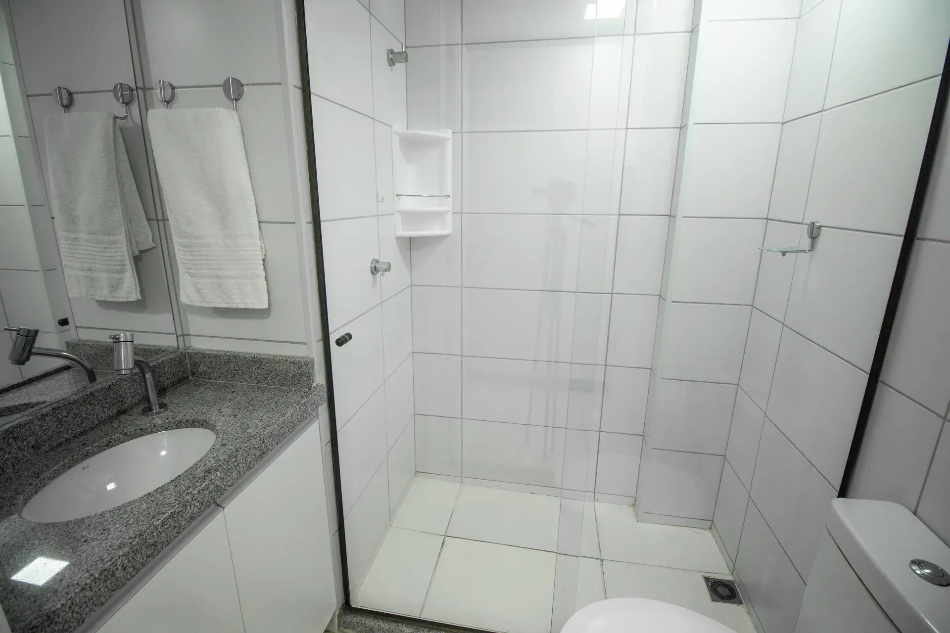 Um banheiro com pia, vaso sanitário, chuveiro e espelho.