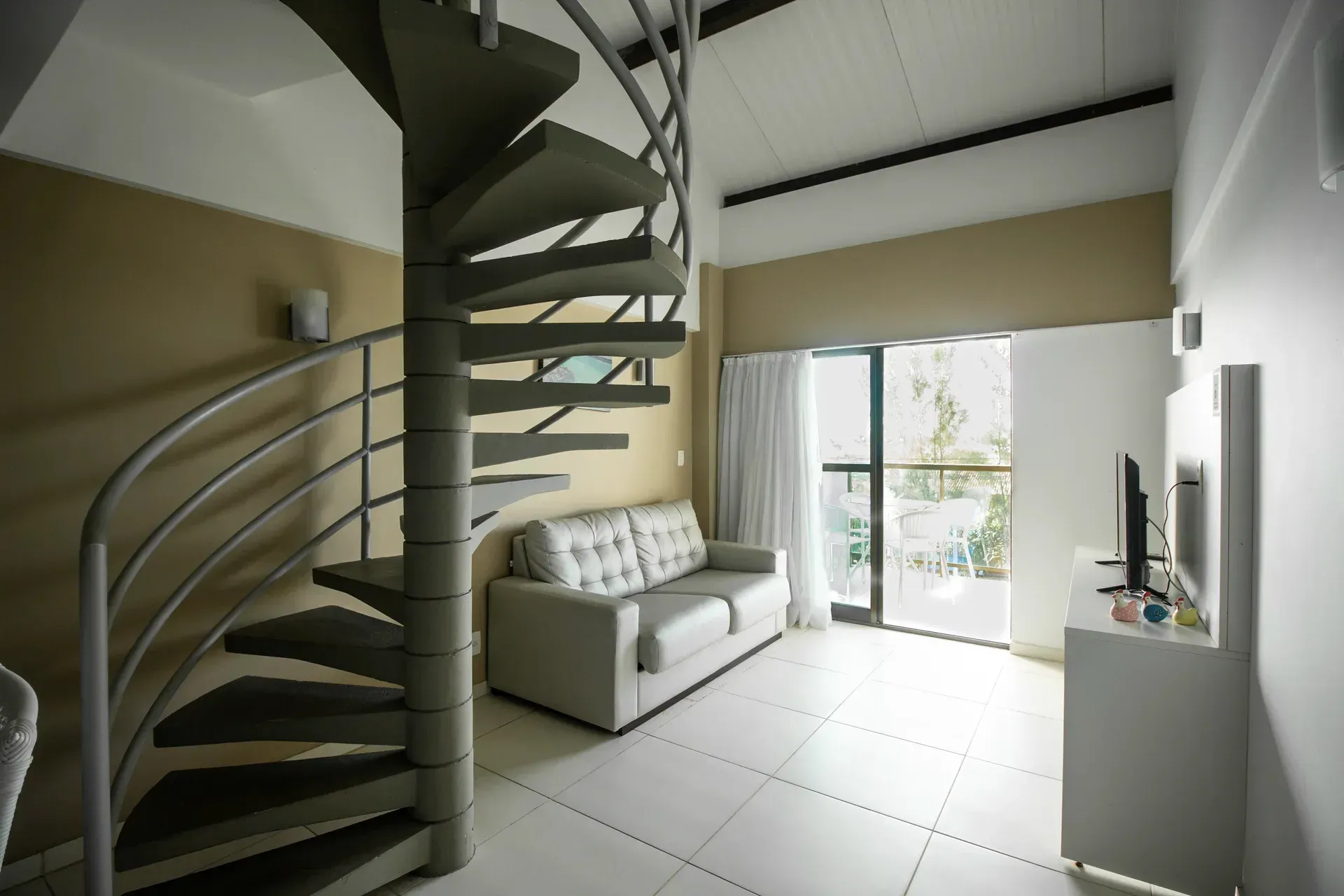 Uma sala de estar com escada em espiral e sofá