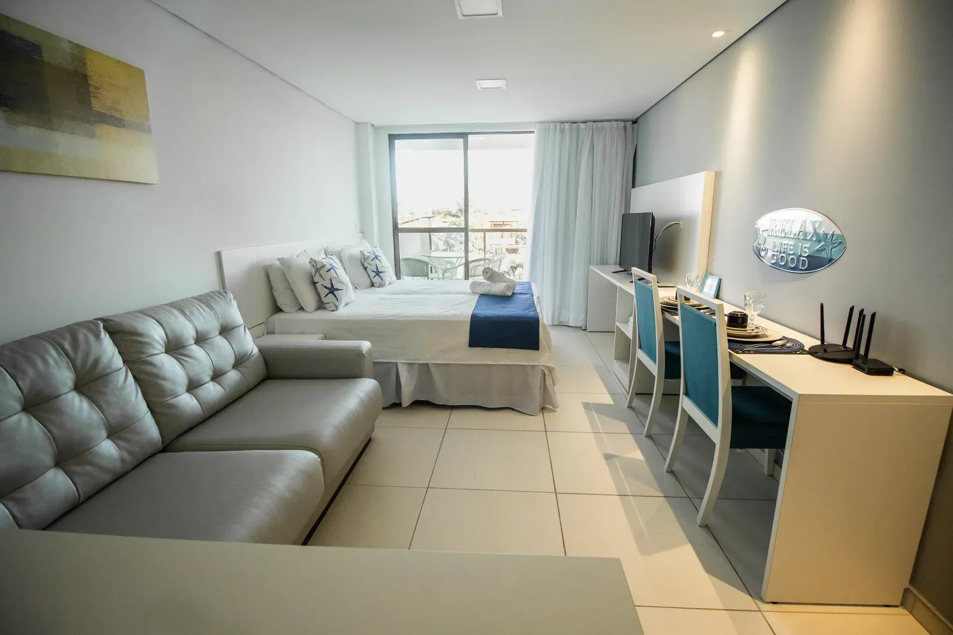 Um quarto de hotel com sofá, mesa, cadeiras e uma cama.