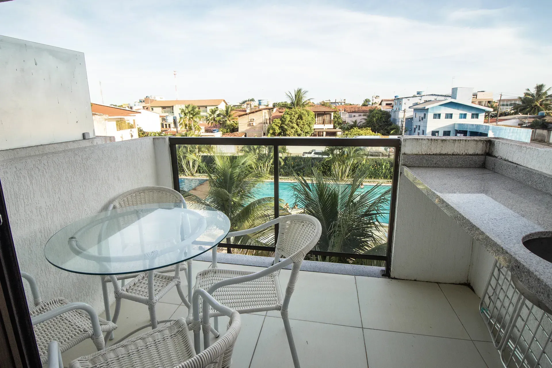 Uma varanda com mesa e cadeiras e vista para a piscina.