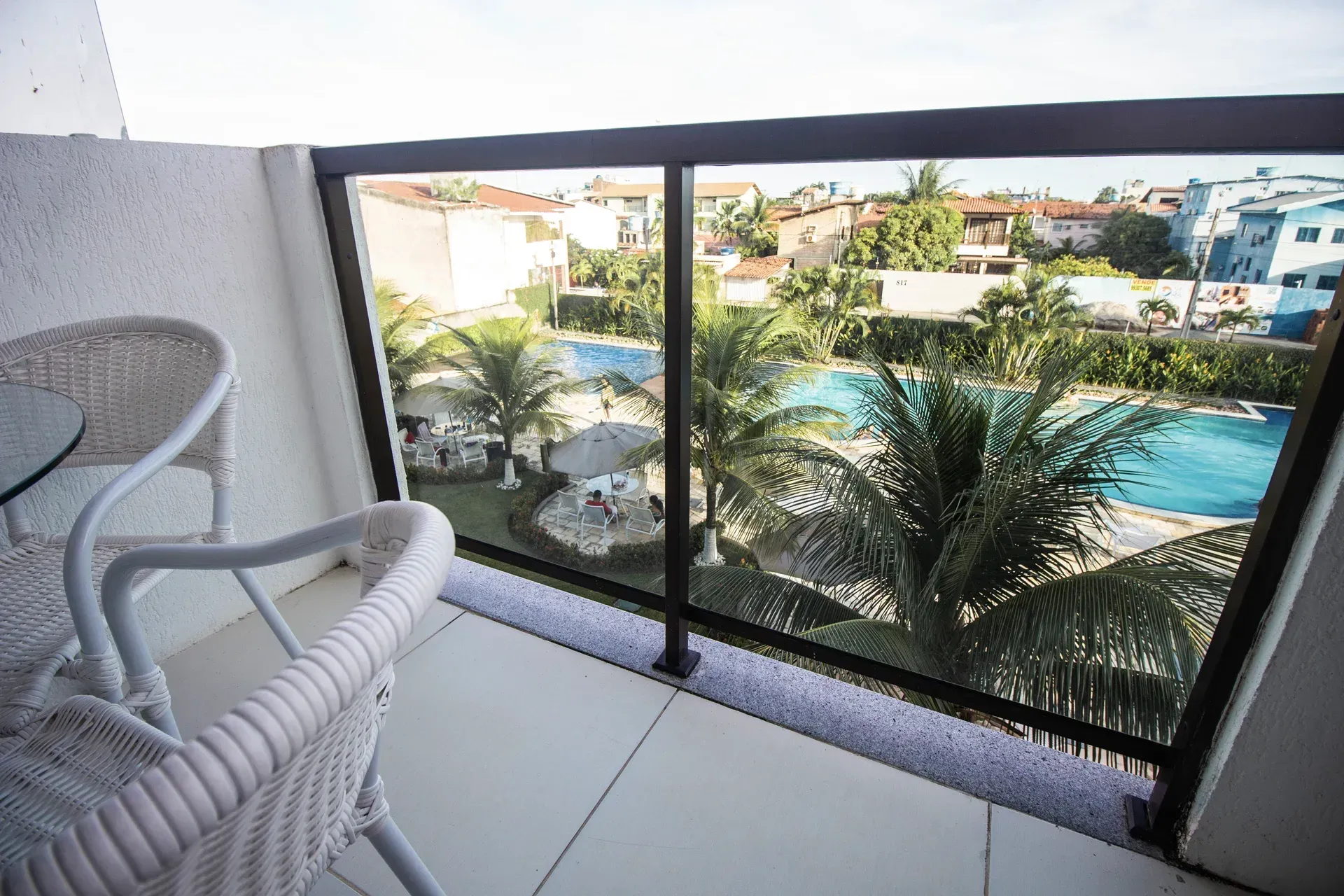 Uma varanda com vista para piscina e palmeiras.