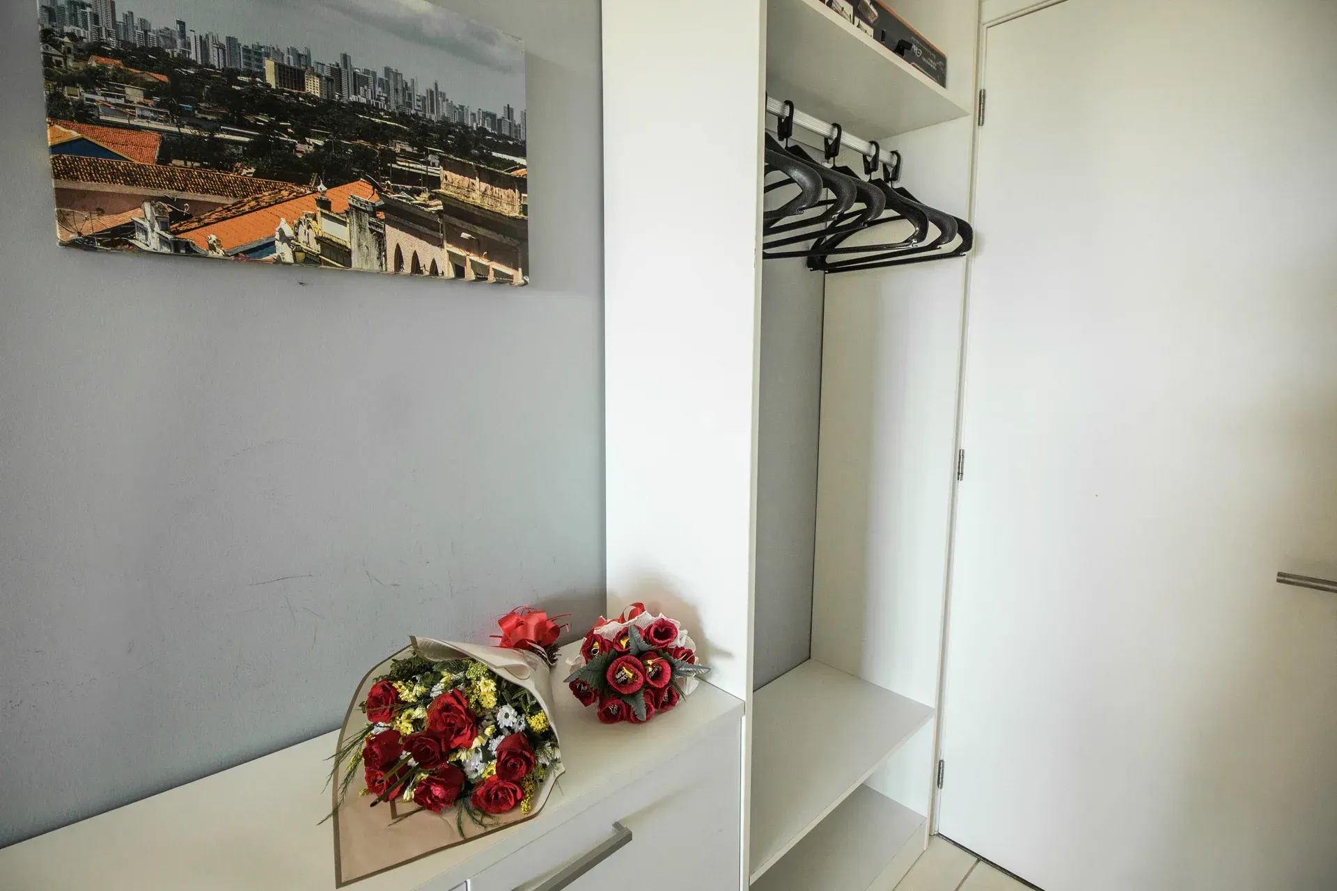 Um quarto com um quadro na parede e uma estante com flores.