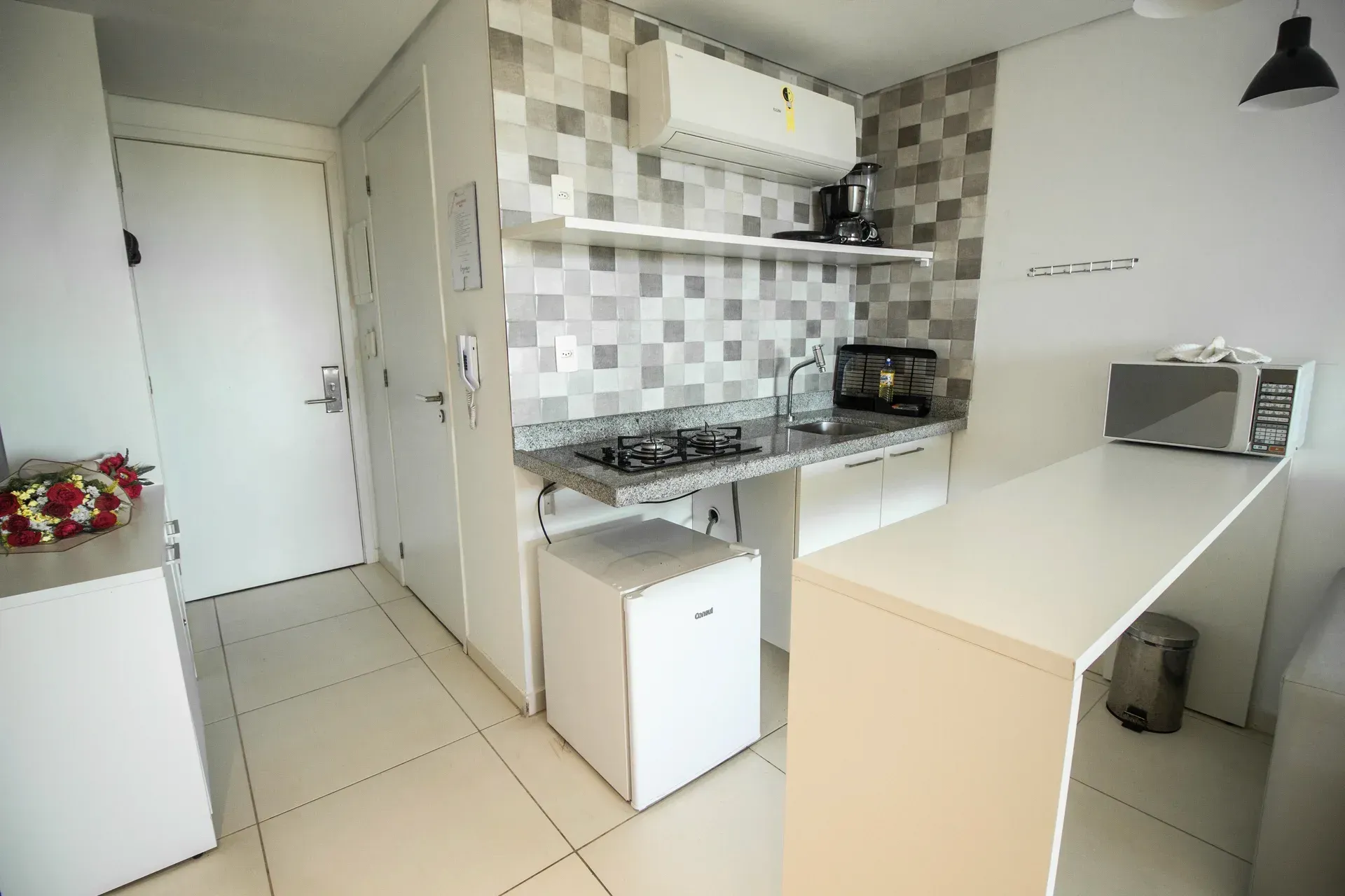 Uma cozinha com fogão, pia, geladeira e micro-ondas.