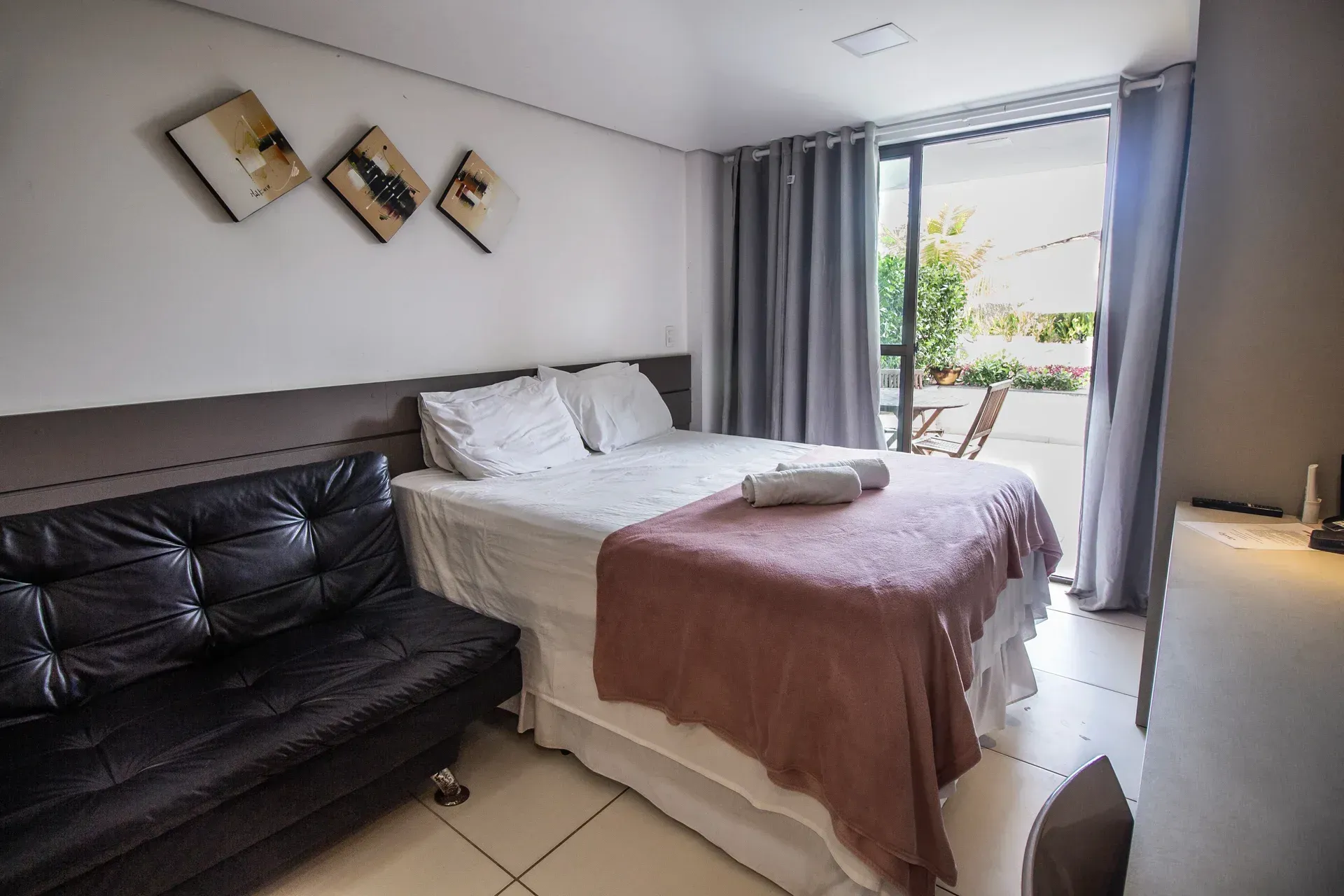 Um quarto de hotel com cama, sofá e portas de correr de vidro.