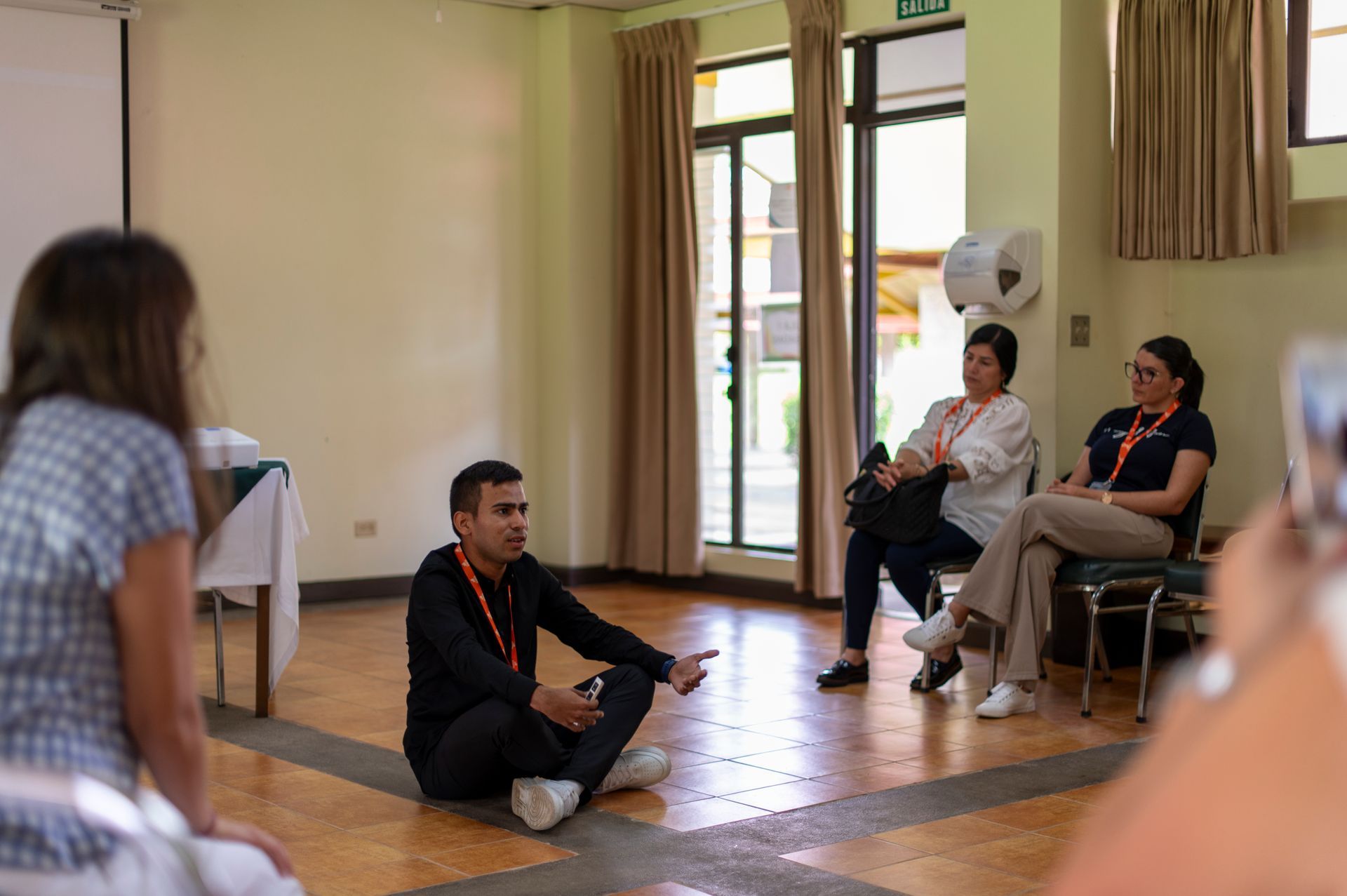 Un grupo de personas está sentado en círculo en el suelo de una habitación.