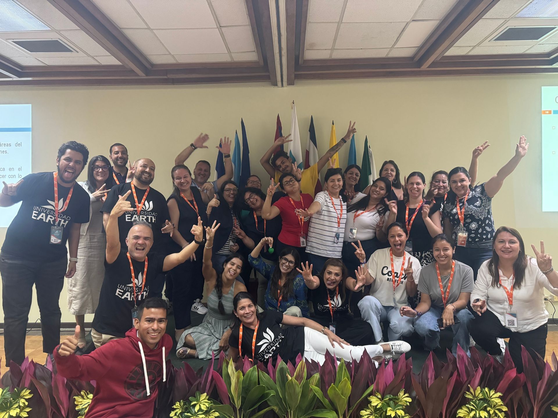 Un grupo de personas sonríe y posa en el escenario con los brazos en alto. Llevan camisetas iguales.