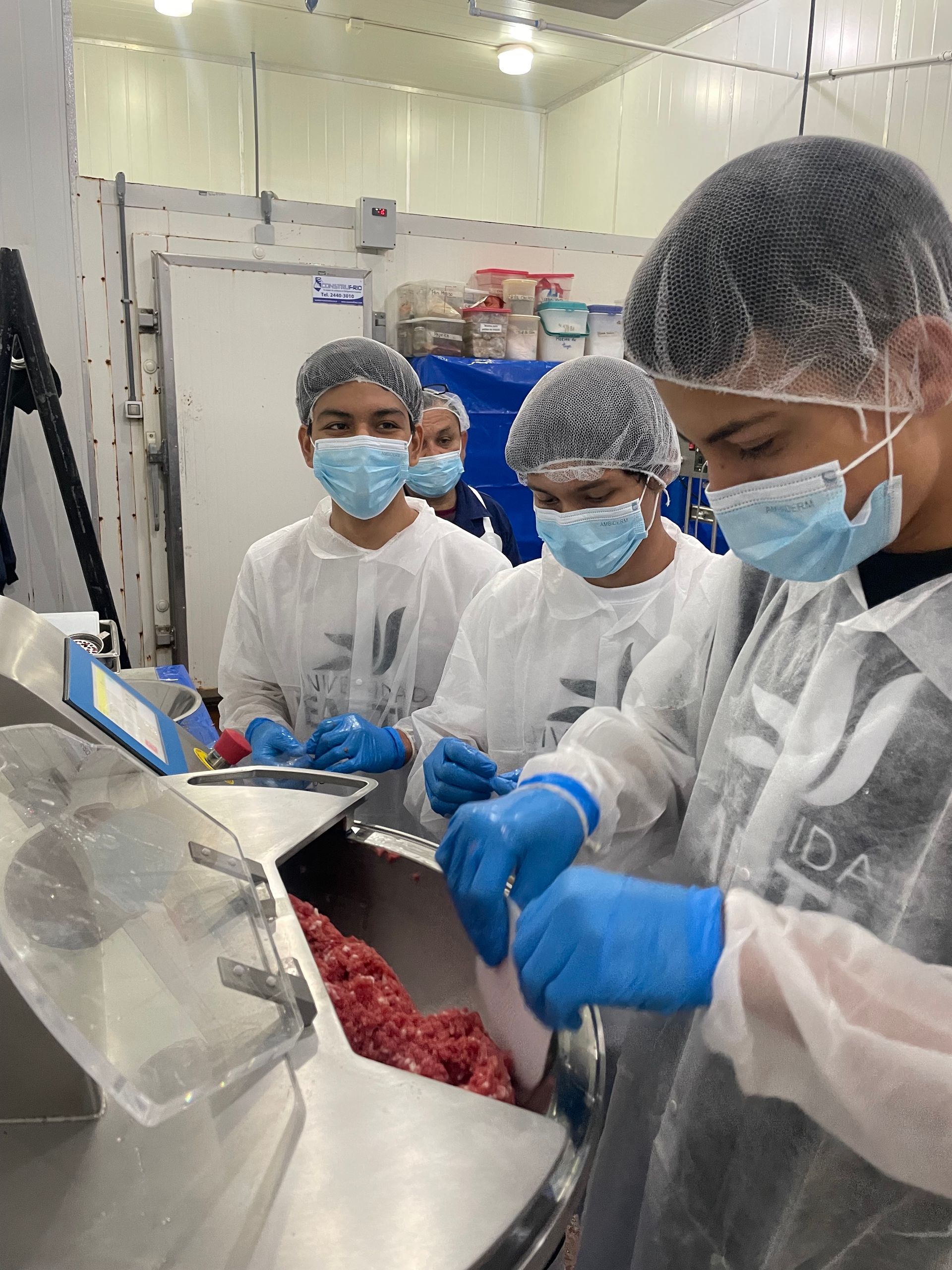 A group of people wearing masks and gloves are working in a kitchen