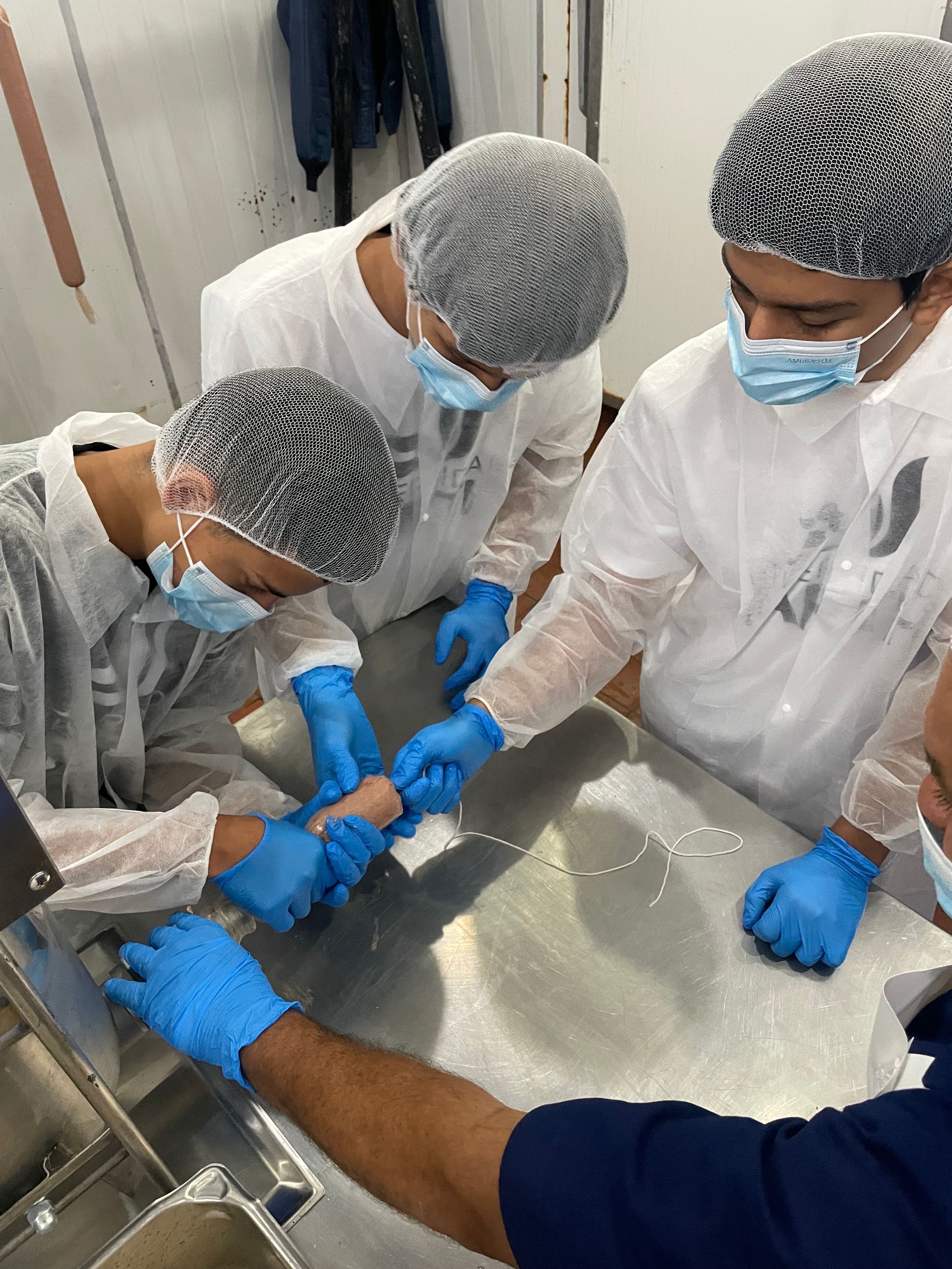 A group of people wearing masks and gloves are working on a table.