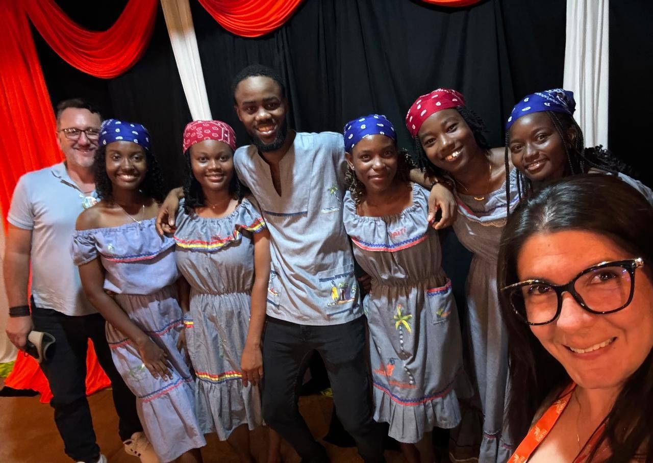 Grupo de personas con atuendo festivo posando para una foto. Fondo rojo y negro.