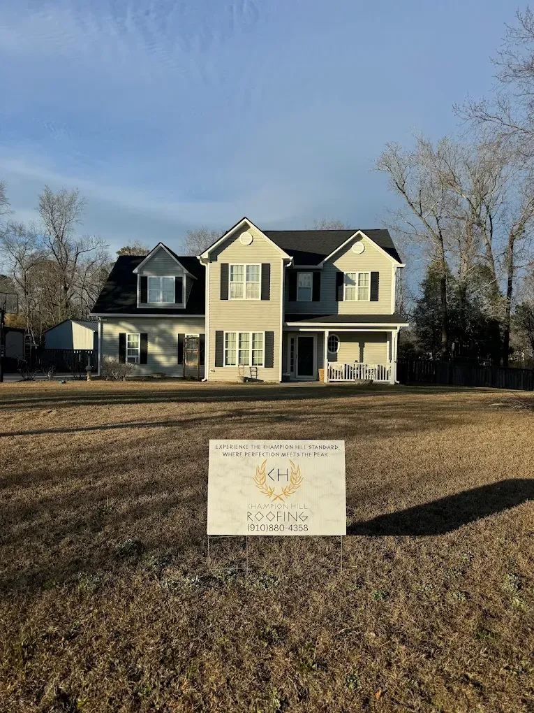 Two-story house with a sign in front on a sunny day.