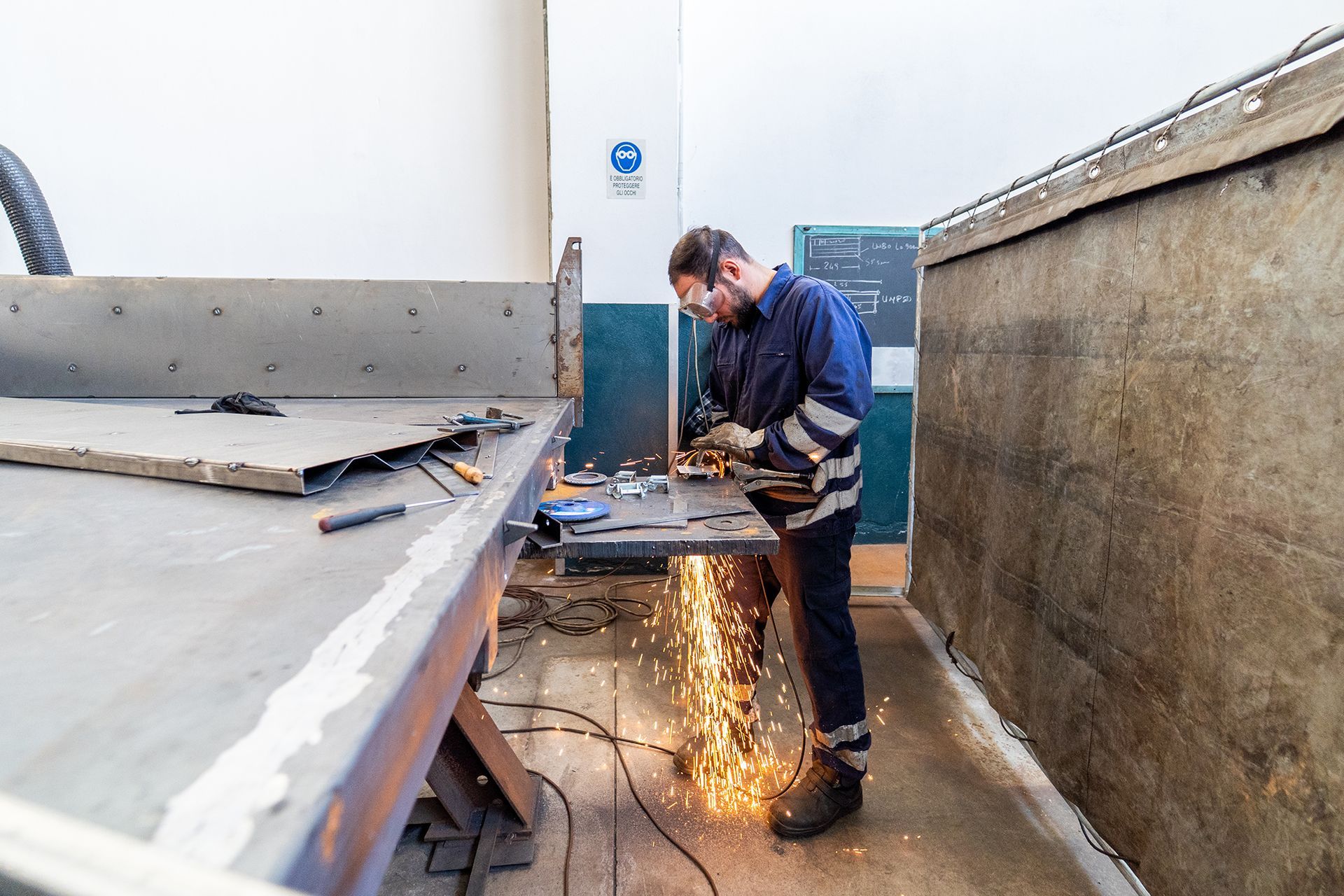 Una persona che usa una smerigliatrice, creando scintille, in un'officina.