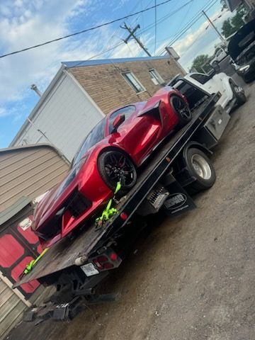 Red sports car strapped on a flatbed tow truck on a street