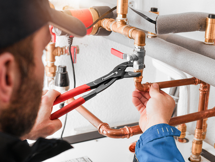 A plumber is fixing a pipe with a pair of pliers.