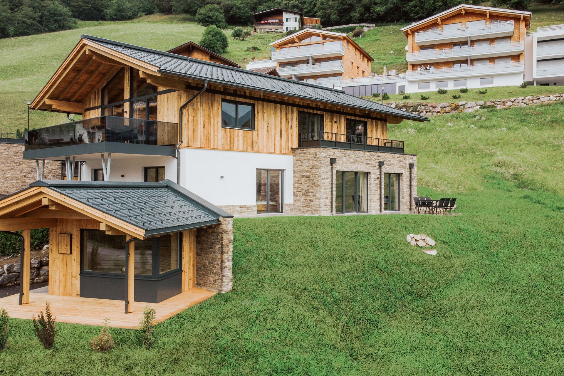 Auf einem grasbewachsenen Hügel steht ein großes Holzhaus.