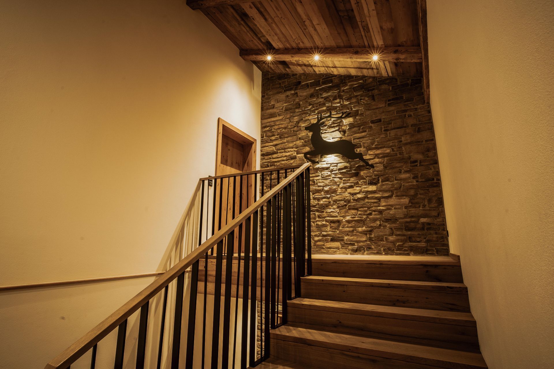 Die Treppe ist aus Holz und Metall und an der Wand hängt ein Hirsch.
