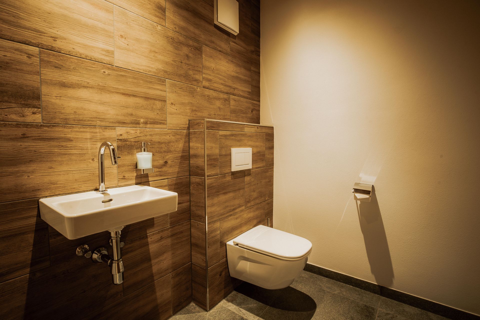 Ein Badezimmer mit Waschbecken, Toilette und Holzwand.