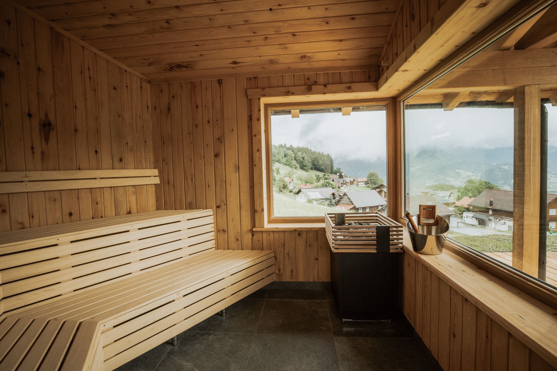 Eine Holzsauna mit Blick auf die Berge und Fenster.