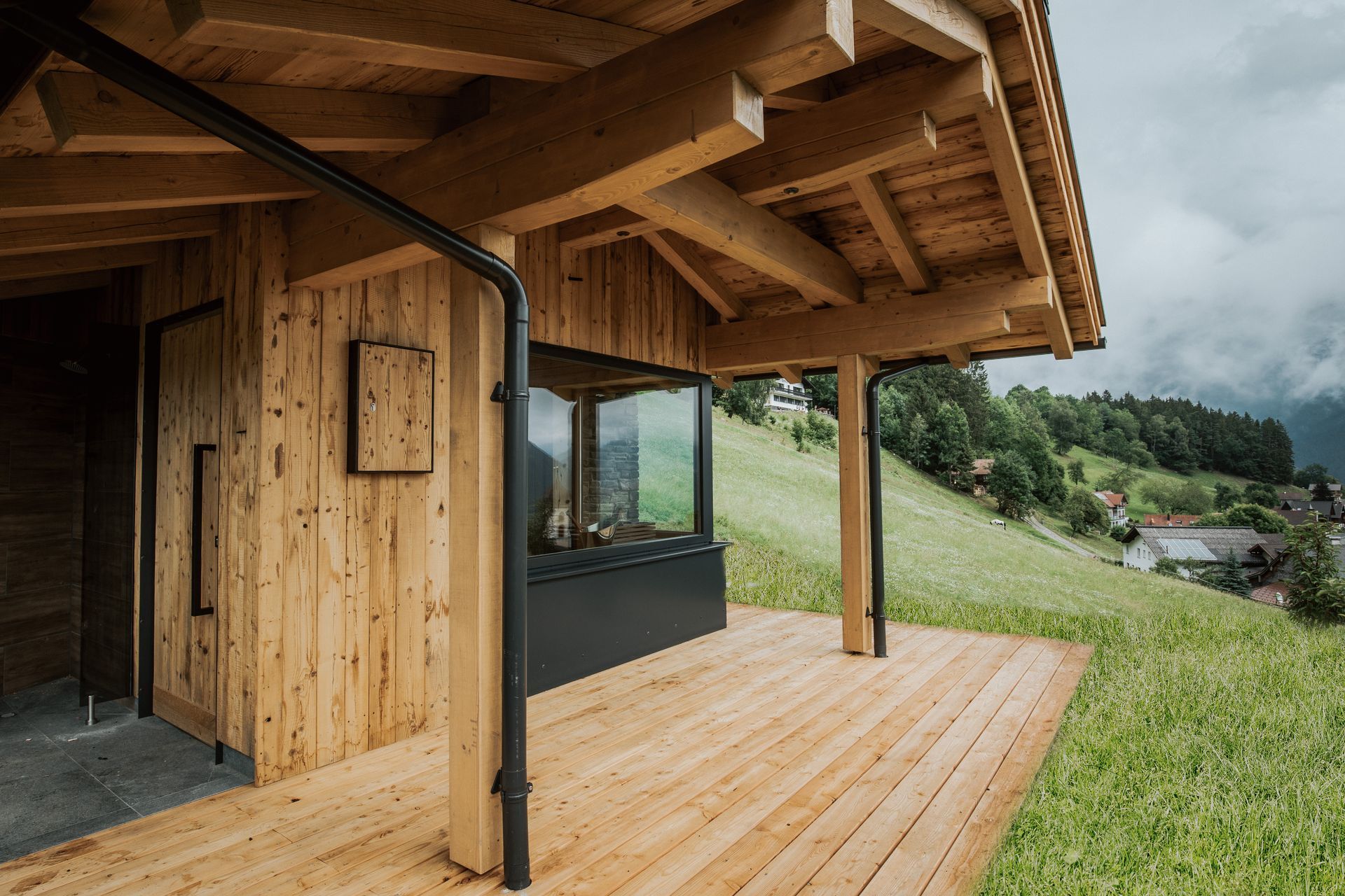 Ein Holzhaus mit Holzterrasse und Blick auf die Berge.