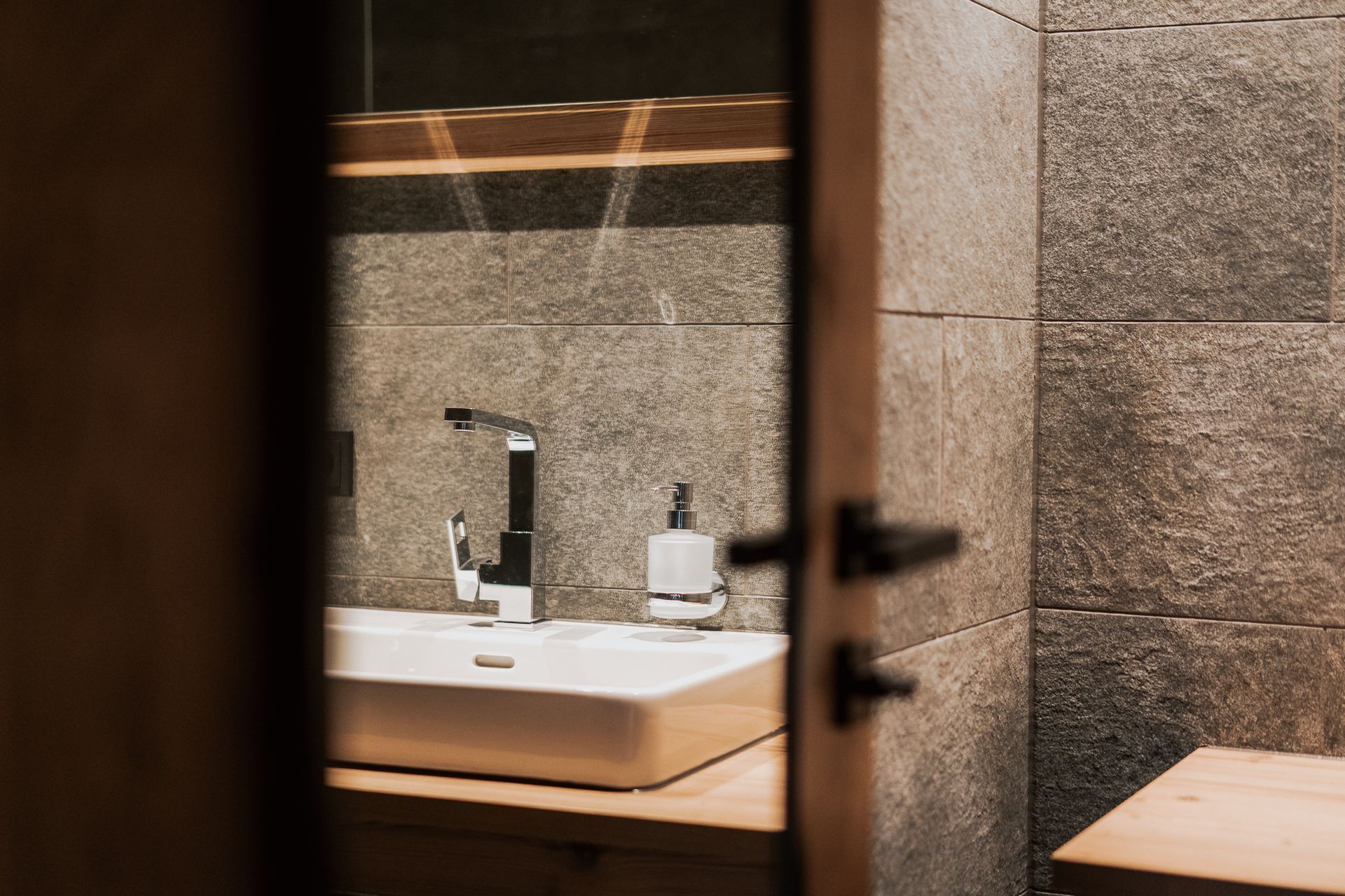 Ein Badezimmer mit Waschbecken und Spiegel hinter einer Glastür.