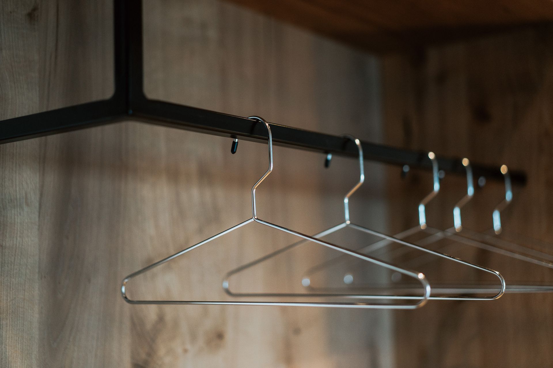 Eine Reihe von Kleiderbügeln aus Metall hängt an einer Stange in einem Schrank.