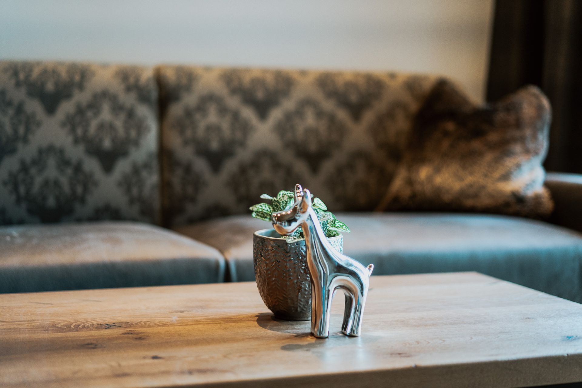 Eine Giraffenfigur sitzt auf einem Holztisch vor einem Sofa.