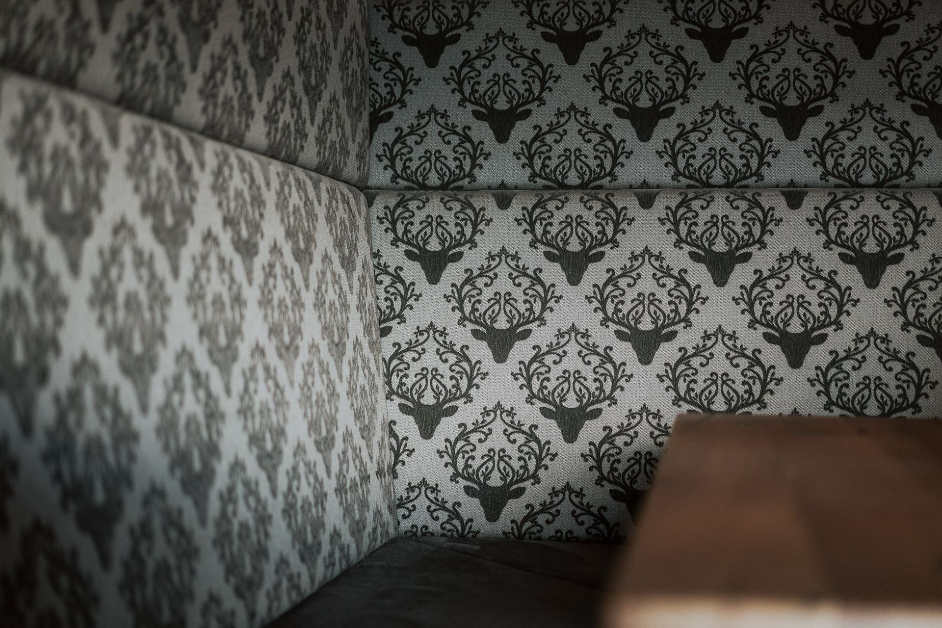 Eine Zimmerecke mit gemusterter Tapete und einem Holztisch.