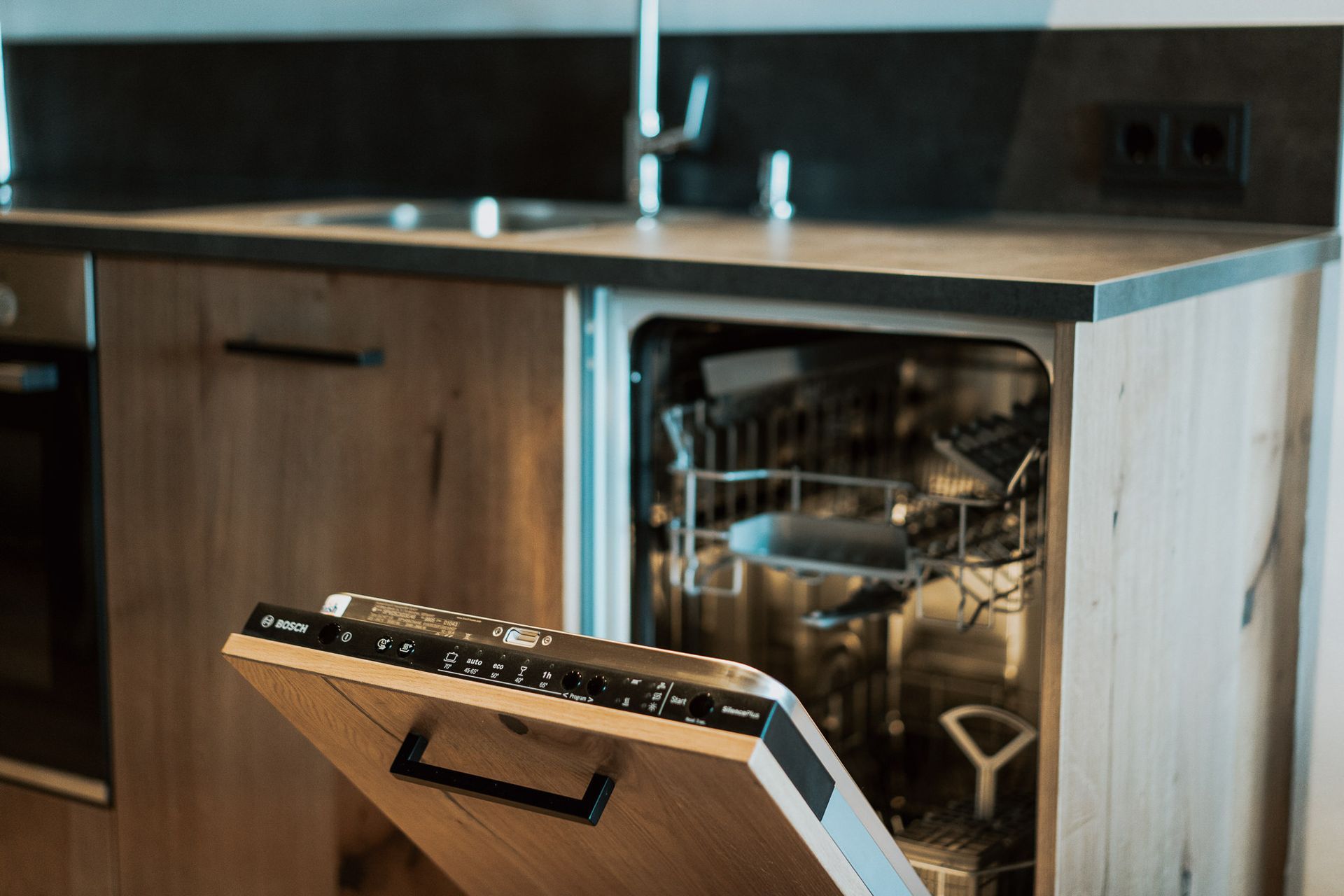 In einer Küche steht ein Geschirrspüler mit geöffneter Tür.