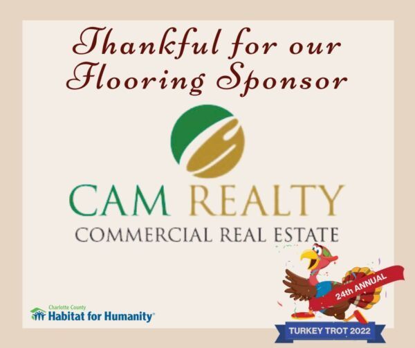 Sign thanking CAM Realty for sponsoring a Turkey Trot. Features logo, text, and a running turkey.