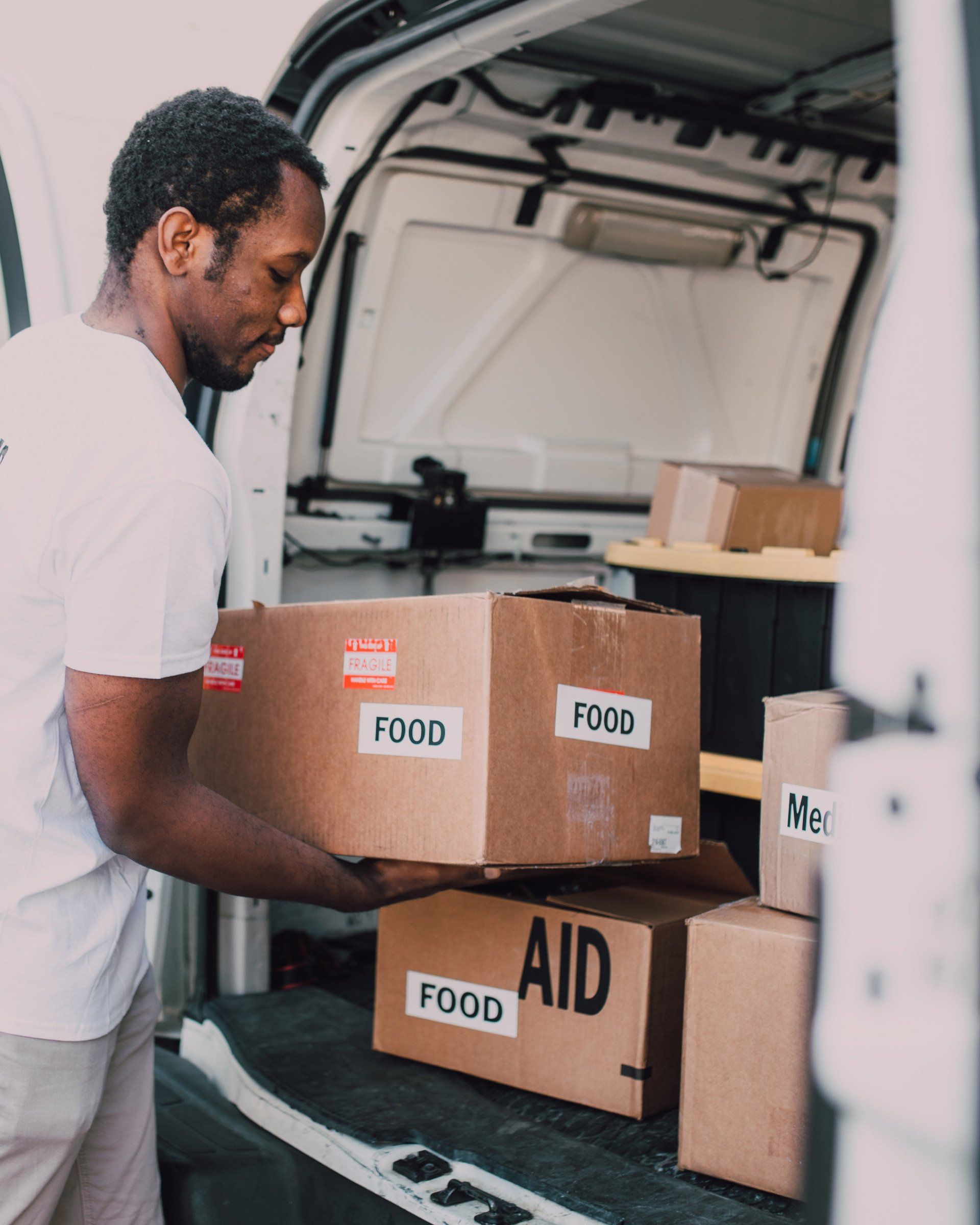 Man in white shirt loading cardboard boxes labeled 