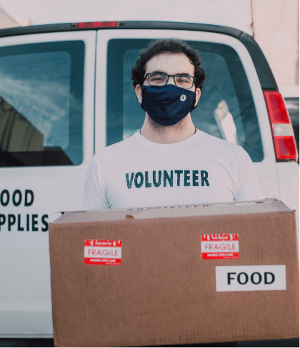 Volunteer wearing a mask, holding a box labeled 