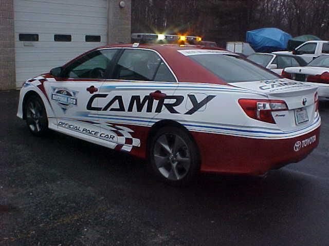 A red and white camry is parked in front of a garage