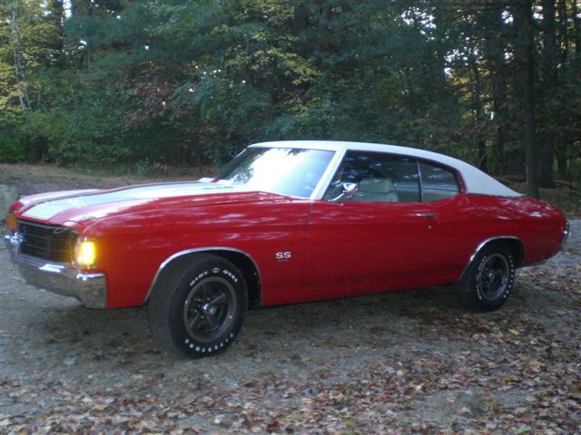 A red and white car is parked on a dirt road