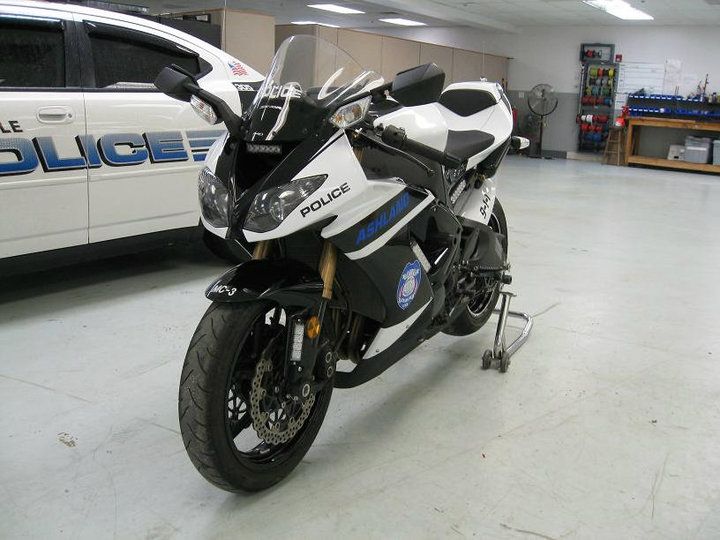A police motorcycle is parked in front of a police car