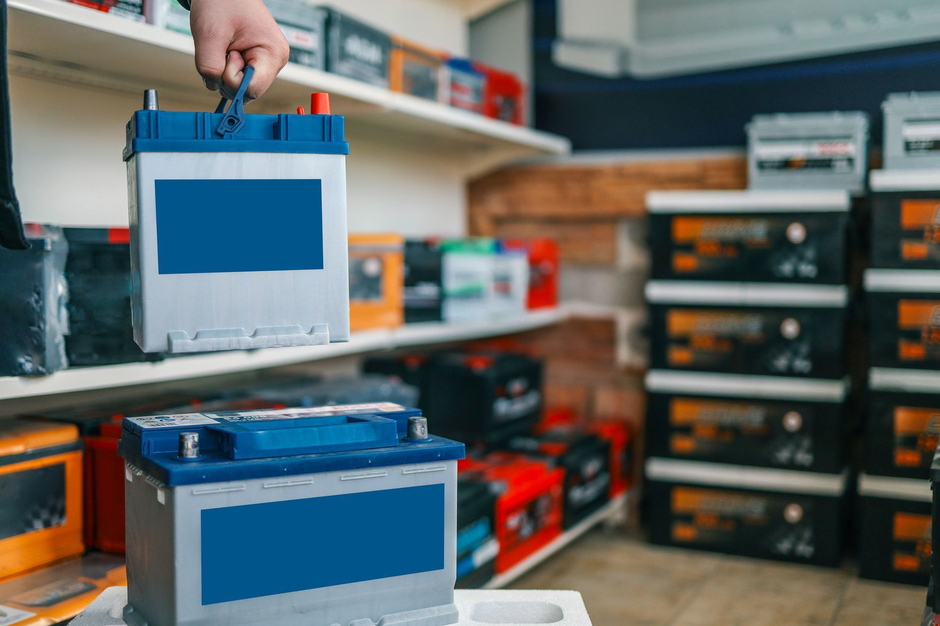 Battery service specialist holding an automotive battery in a used battery store.