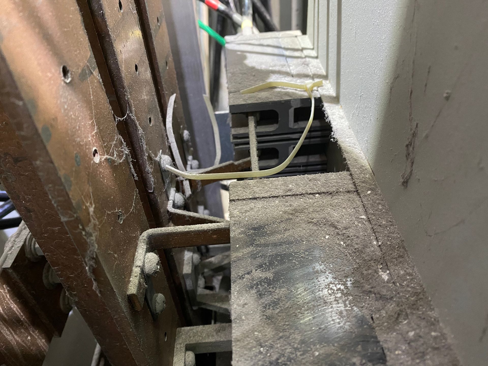 Narrow outdoor walkway with wooden railing, white wall, and a hose or cable on the ground.
