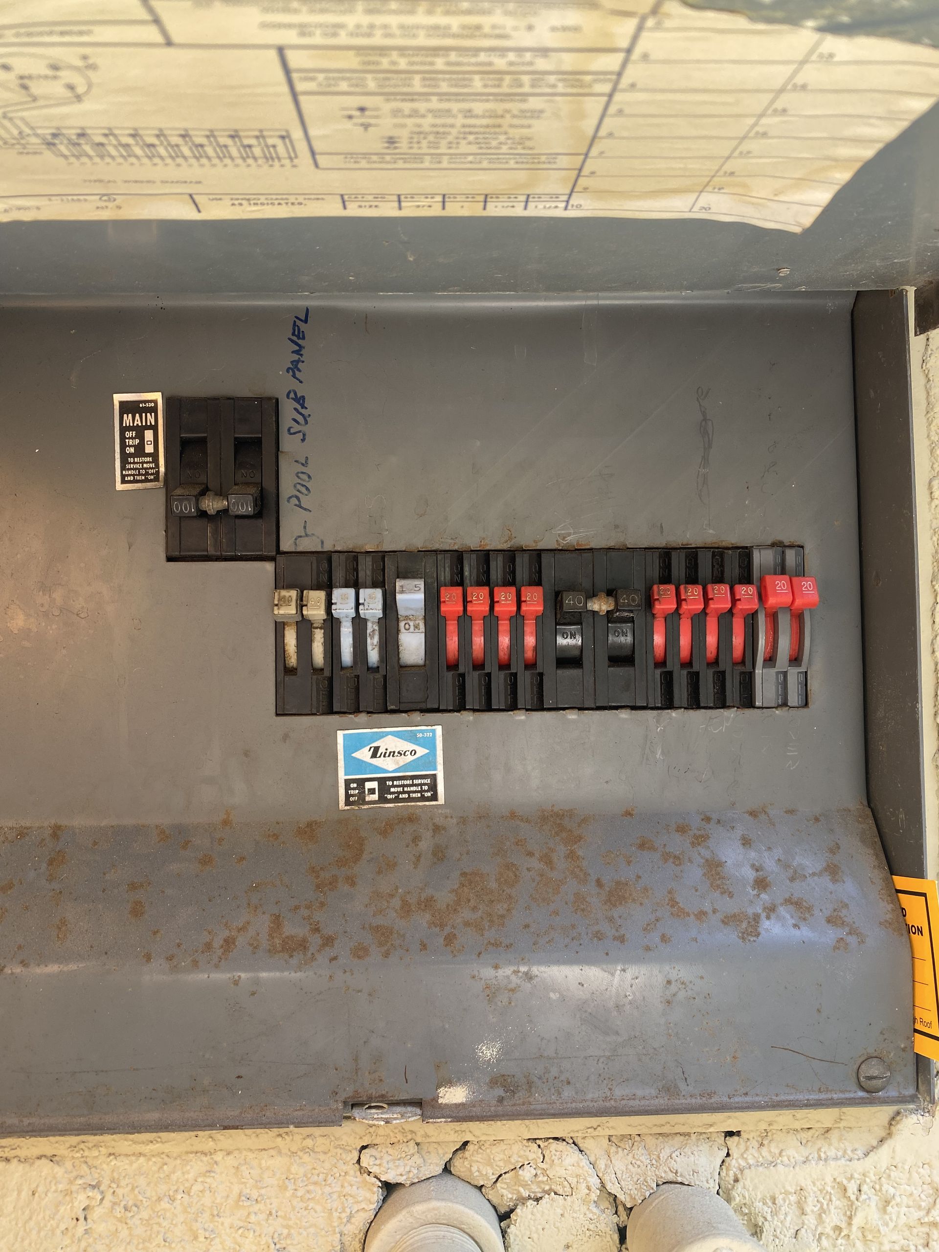Open electrical breaker panel with rows of red and black switches and a small warning label.