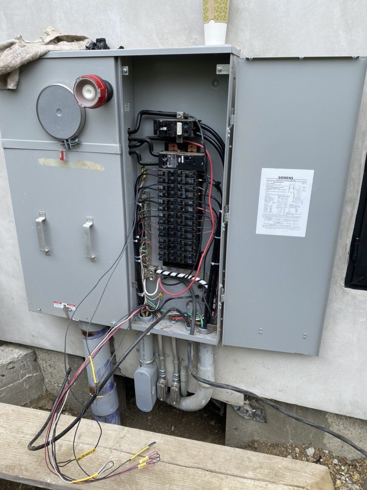 Open electrical service panel with a meter socket on the left and circuit breakers inside on the right, outdoors.