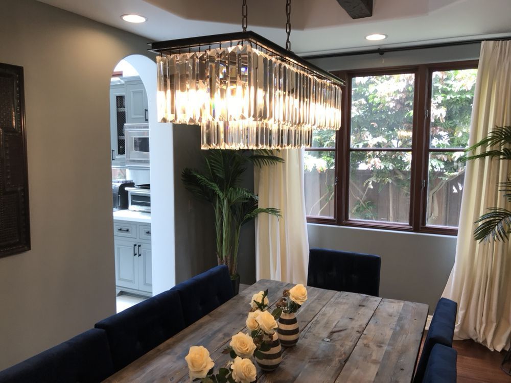 A man is standing on a ladder holding a wire.