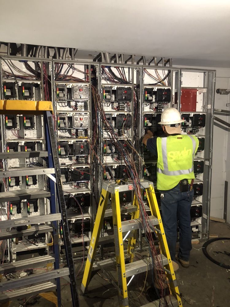 Two men wearing hard hats are working on a machine.