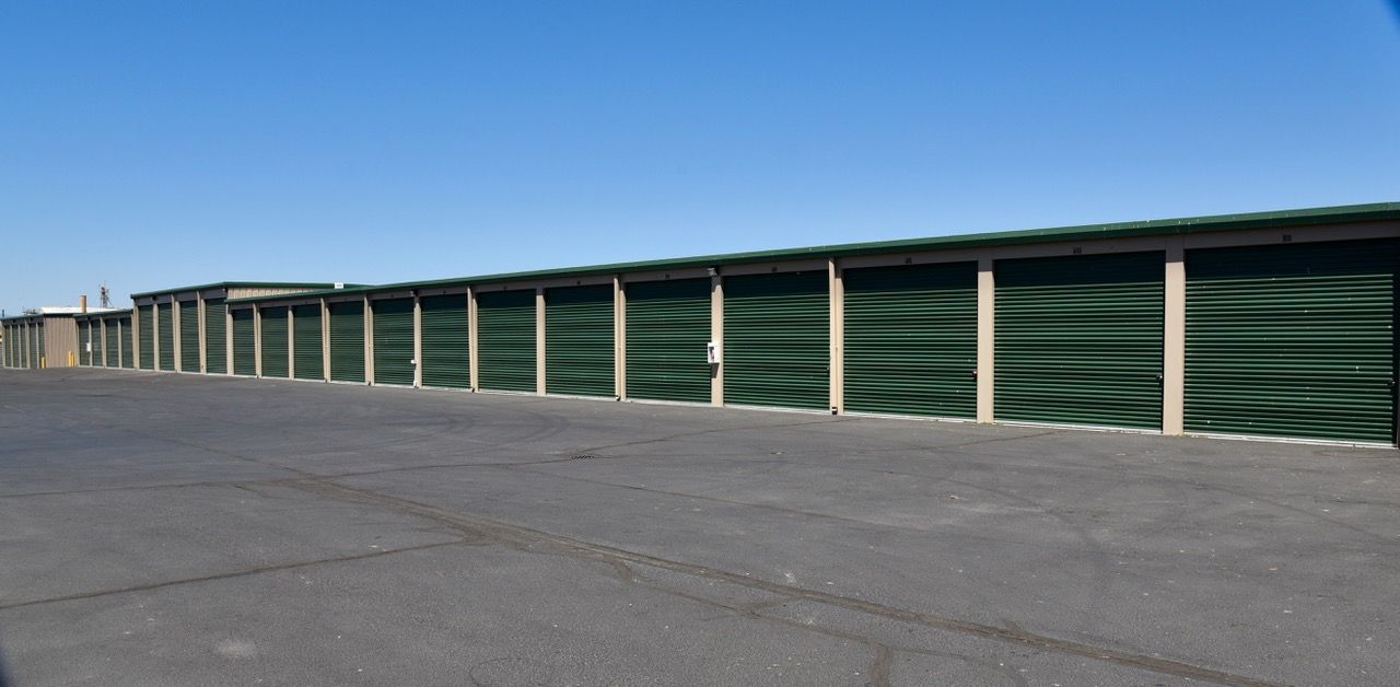 A row of green storage units with a blue sky in the background