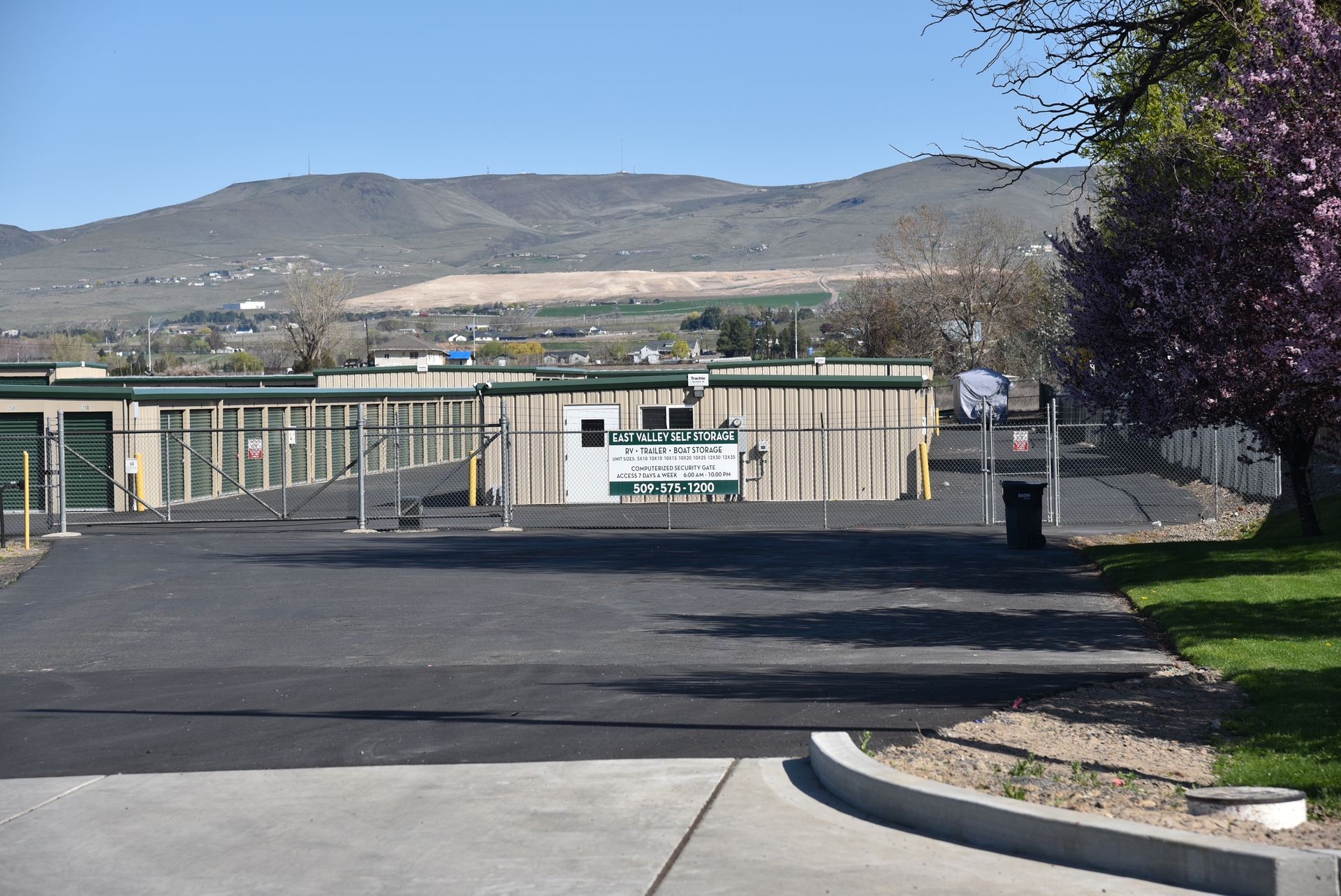 A driveway leading to a storage facility with mountains in the background.