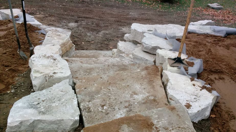 A pile of rocks and a shovel in the dirt.