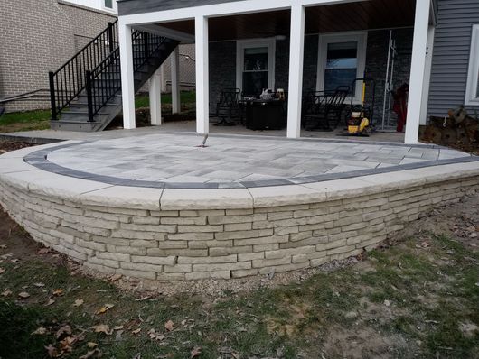 A patio with a brick wall in front of a house.