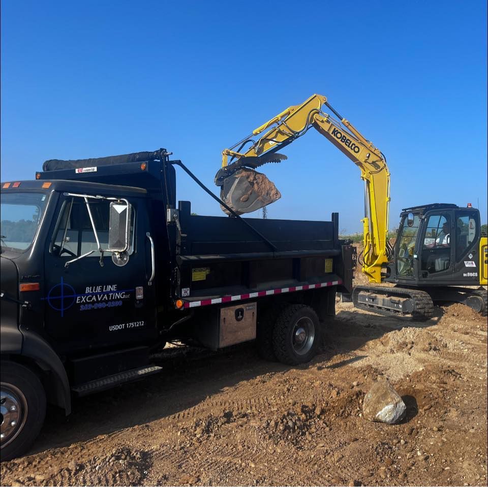 A kobelco excavator is loading dirt into a dump truck