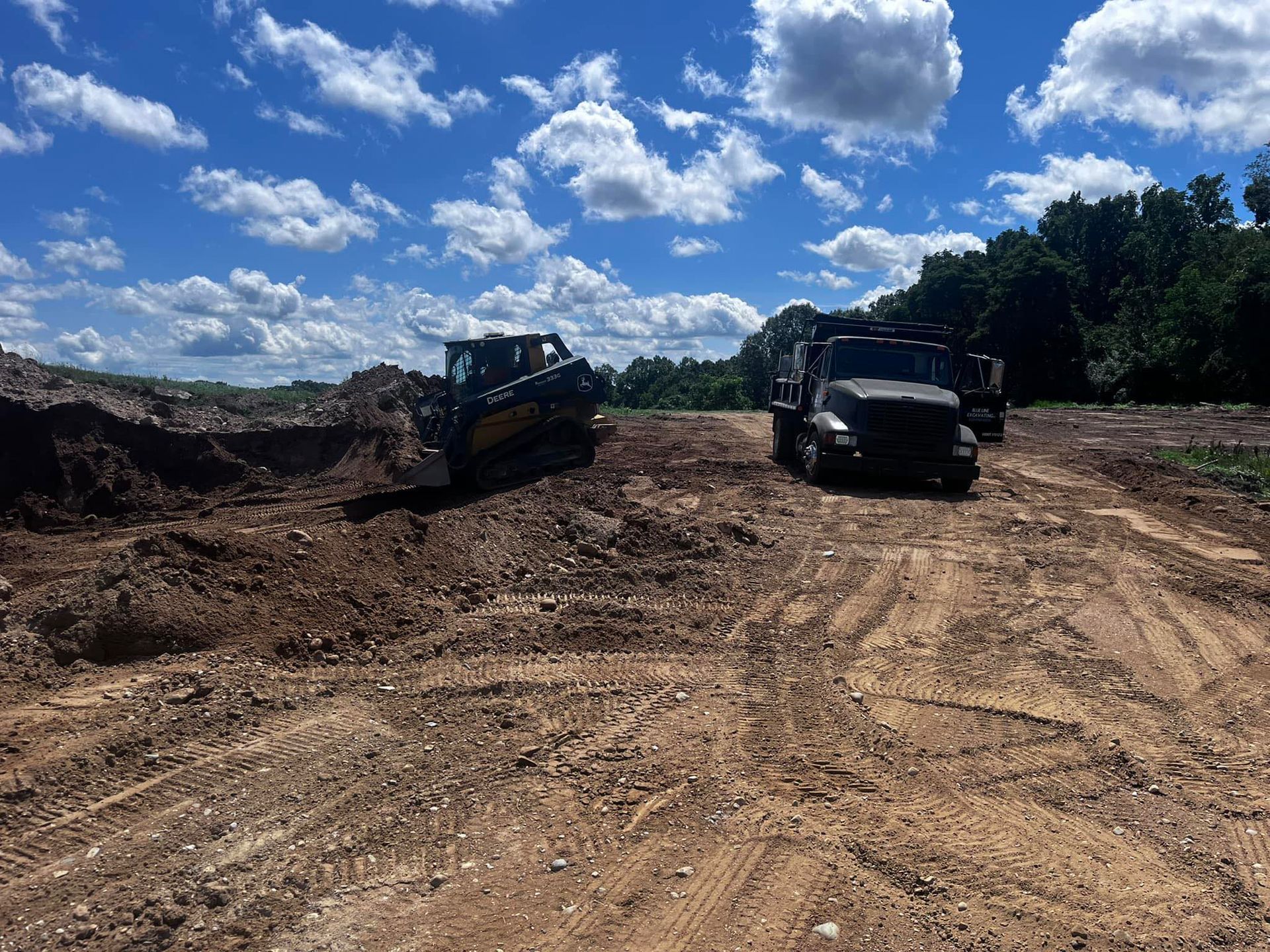 A bulldozer and a truck are driving down a dirt road.