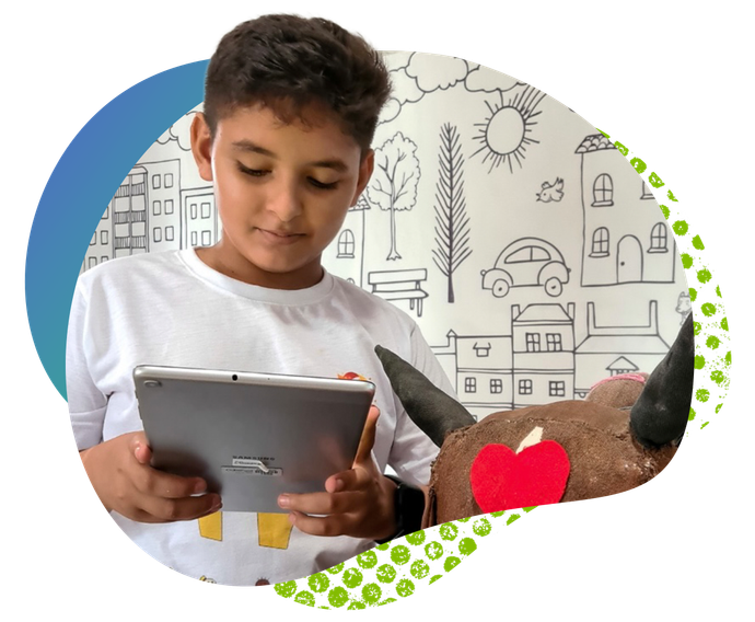 Uma pessoa vestindo uma camisa branca olha para um tablet em frente a uma parede com desenhos 