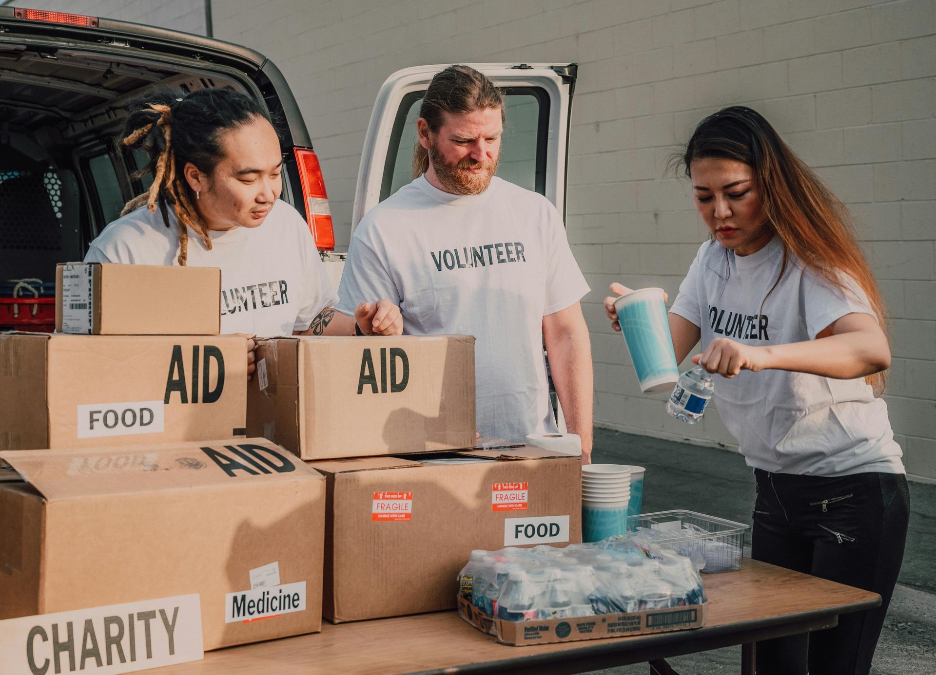 A group of volunteers are loading boxes into a van. - abraham sanieoff